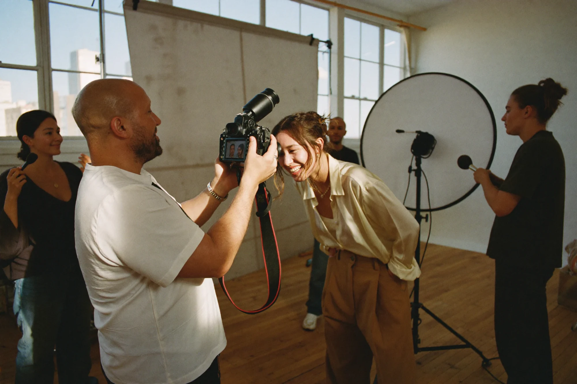 A photographer shows a shot on camera to a smiling model during a studio session.